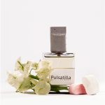 تصویر عطر پولساتیلا کلار 50 میل برای بانوان، کنار گل‌های سفید و پاستیلی – رایحه گلی، مرکباتی و پاستیلی